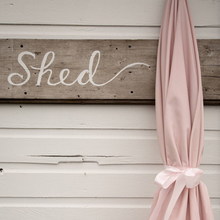 Load image into Gallery viewer, Wooden sign with 'Shed' on a wooden wall with pink curtains.
