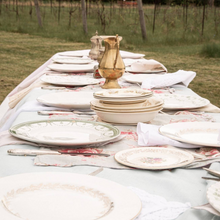 Load image into Gallery viewer, Dining table set with plates, cutlery, and a vase outdoors.